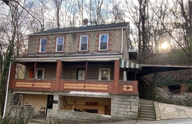 view of front of home with a balcony, a chimney, and stone siding