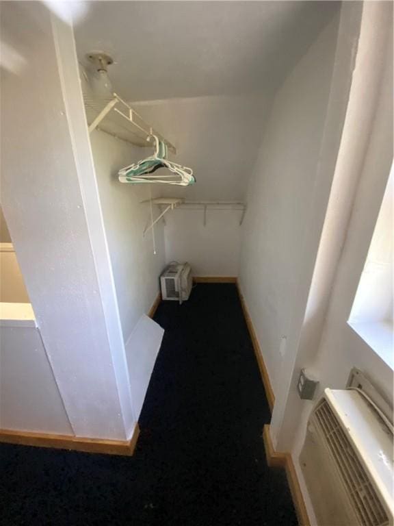spacious closet featuring a wall mounted air conditioner, lofted ceiling, and carpet flooring