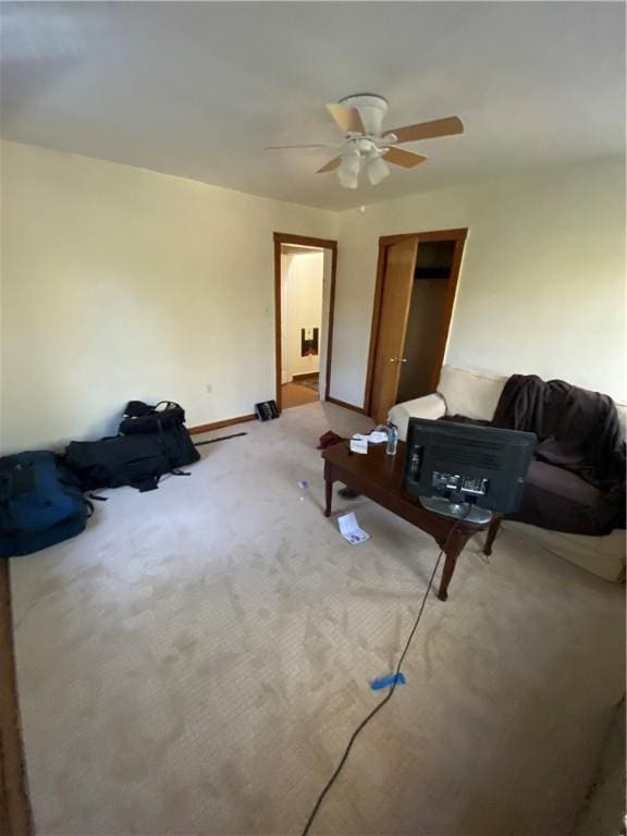 carpeted living room featuring baseboards and a ceiling fan