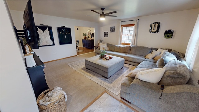 living area with a ceiling fan, light colored carpet, and baseboards