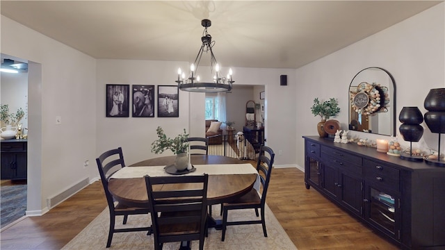 dining room featuring dark wood-type flooring, a chandelier, and baseboards