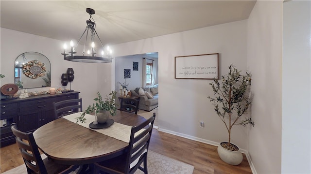 dining space with wood finished floors, baseboards, and a chandelier