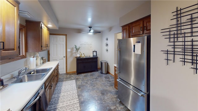 kitchen featuring appliances with stainless steel finishes, a sink, a ceiling fan, light countertops, and baseboards