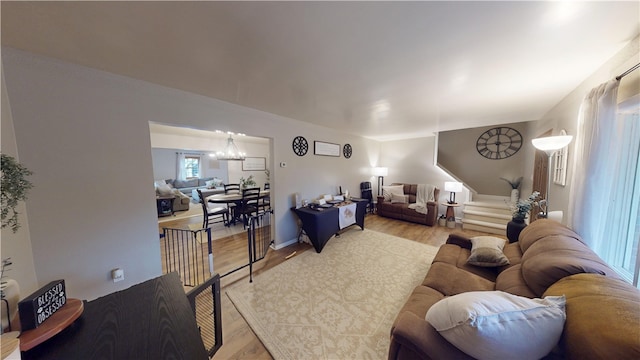 living room featuring a chandelier, light wood-type flooring, and stairway