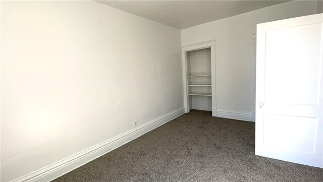unfurnished bedroom featuring baseboards and dark colored carpet