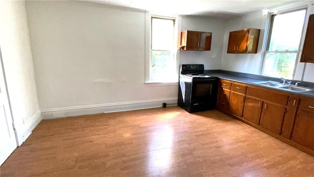 kitchen featuring dark countertops, light wood-type flooring, black range with electric stovetop, a sink, and baseboards