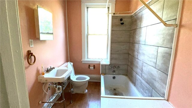 full bath with toilet, a sink, shower / washtub combination, and wood finished floors