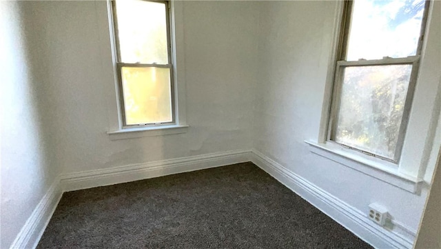 unfurnished room featuring dark carpet and baseboards
