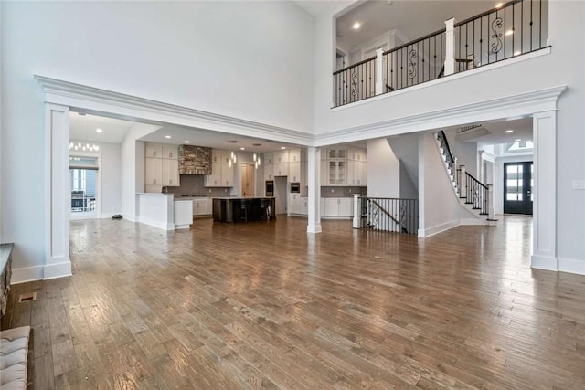671 Chilliwack Ln, Marshall, PA 16046 - unfurnished living room featuring a towering ceiling, baseboards, stairs, visible vents, and wood finished floors