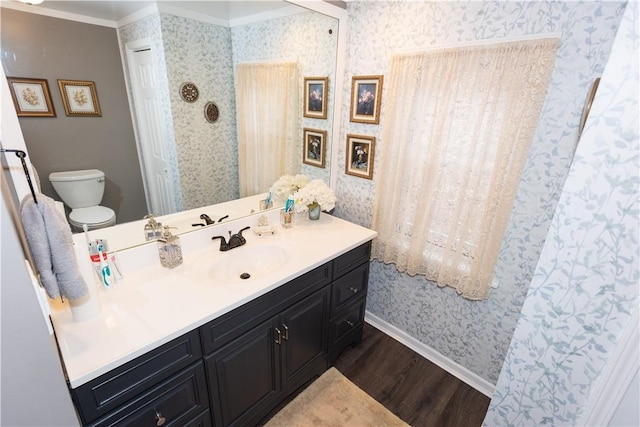 bathroom featuring wallpapered walls, wood finished floors, baseboards, vanity, and toilet
