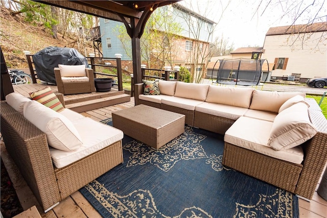 wooden terrace featuring a trampoline, an outdoor living space, and area for grilling