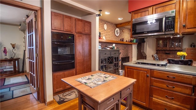 612 Freeport Rd, South Buffalo Twp, PA 16229 - kitchen with a warming drawer, appliances with stainless steel finishes, light wood finished floors, brown cabinetry, and brick wall