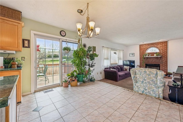dining space with visible vents, light tile patterned floors, a notable chandelier, a brick fireplace, and light carpet