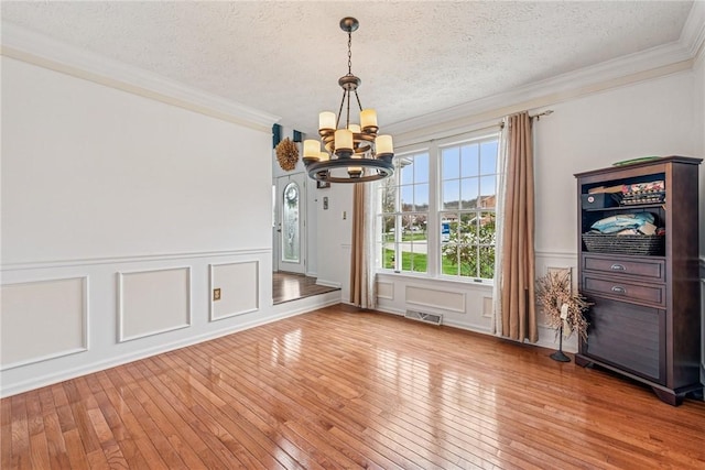 114 Adella Ct, Penn Twp Wml, PA 15644 - unfurnished dining area featuring a chandelier, ornamental molding, a textured ceiling, hardwood / wood-style flooring, and a decorative wall