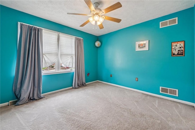 carpeted empty room featuring visible vents, a textured ceiling, baseboards, and ceiling fan