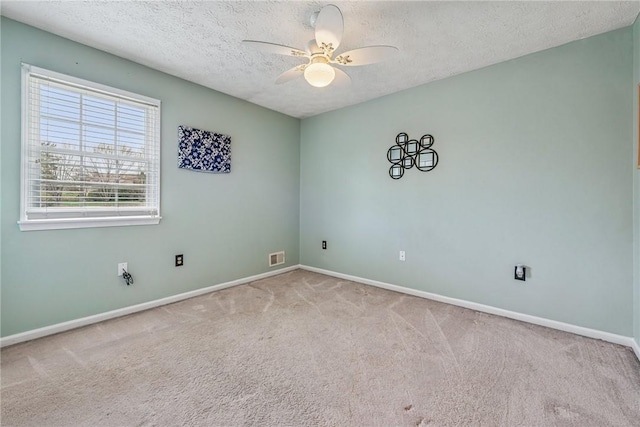 carpeted empty room with visible vents, baseboards, a ceiling fan, and a textured ceiling