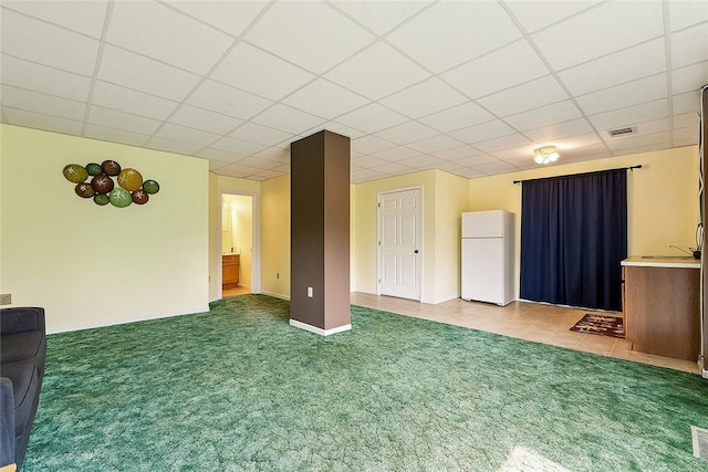 unfurnished living room with carpet flooring, visible vents, and a drop ceiling