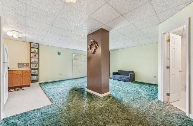below grade area featuring carpet flooring, baseboards, and a drop ceiling
