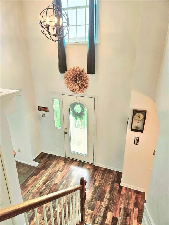 entrance foyer with baseboards, a high ceiling, an inviting chandelier, and wood finished floors