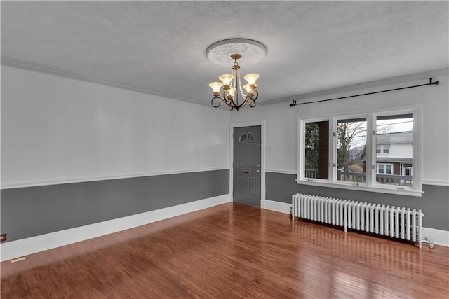 115 Powell St, Wilkins Twp, PA 15112 - spare room with radiator heating unit, a chandelier, wood finished floors, baseboards, and a textured ceiling