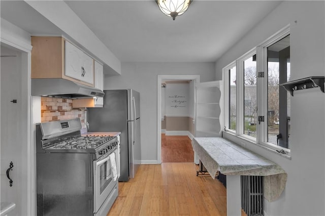 115 Powell St, Wilkins Twp, PA 15112 - kitchen featuring appliances with stainless steel finishes, under cabinet range hood, baseboards, light wood finished floors, and tasteful backsplash
