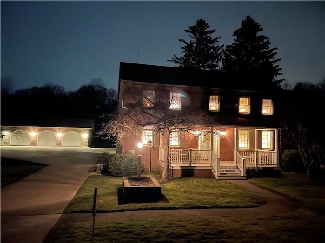 view of front of home with covered porch, an outbuilding, concrete driveway, and a yard