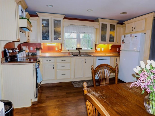 kitchen featuring white appliances, recessed lighting, dark wood-type flooring, glass insert cabinets, and a sink