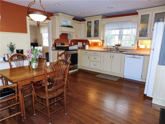 kitchen featuring white appliances, dark wood-type flooring, a sink, glass insert cabinets, and wainscoting