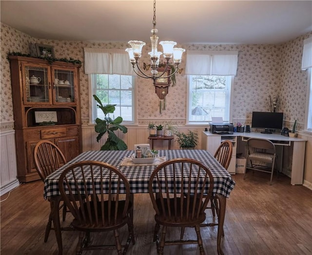 dining area with wallpapered walls, an inviting chandelier, wainscoting, and wood finished floors