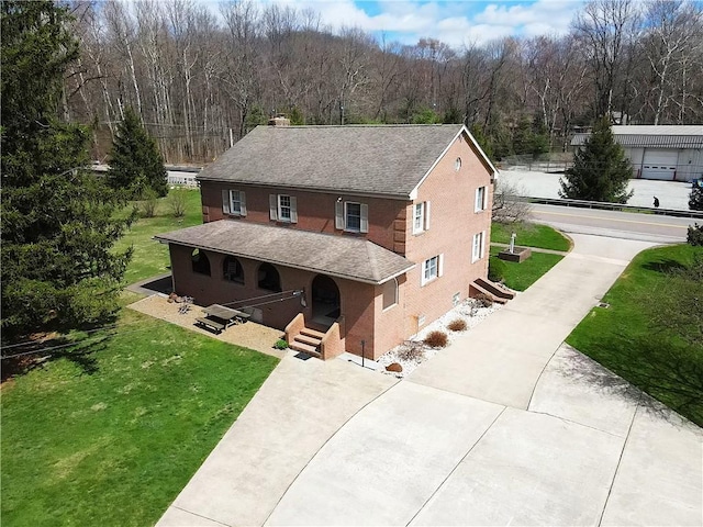 view of front of property with a chimney, concrete driveway, a front yard, roof with shingles, and stucco siding