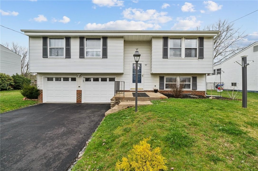 split foyer home with brick siding, a front yard, aphalt driveway, and a garage