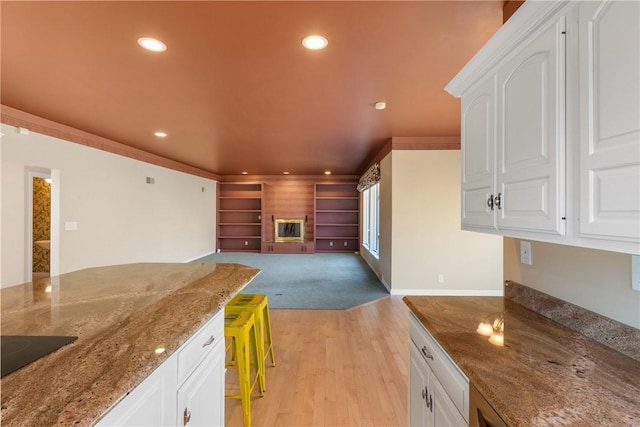 2036 Revere Dr, Connellsville, PA 15425 - kitchen with recessed lighting, light wood finished floors, white cabinets, a glass covered fireplace, and stone countertops