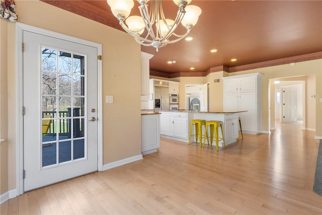 2036 Revere Dr, Connellsville, PA 15425 - kitchen featuring a chandelier, white cabinets, recessed lighting, light wood-type flooring, and a kitchen breakfast bar