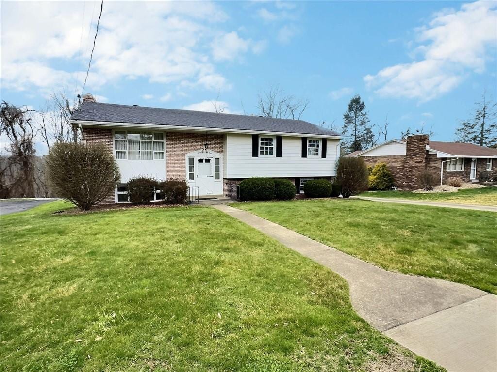 bi-level home featuring a front lawn and brick siding