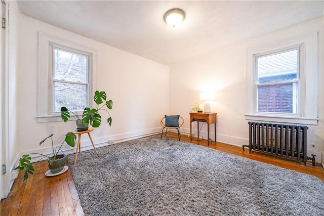 sitting room featuring a wealth of natural light, radiator heating unit, hardwood / wood-style flooring, and baseboards