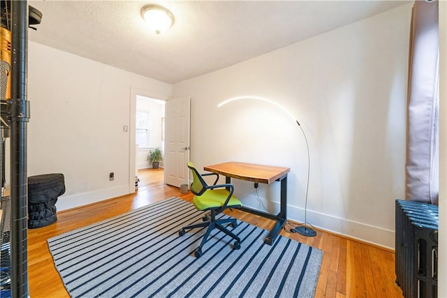 office area with baseboards, wood finished floors, and a textured ceiling