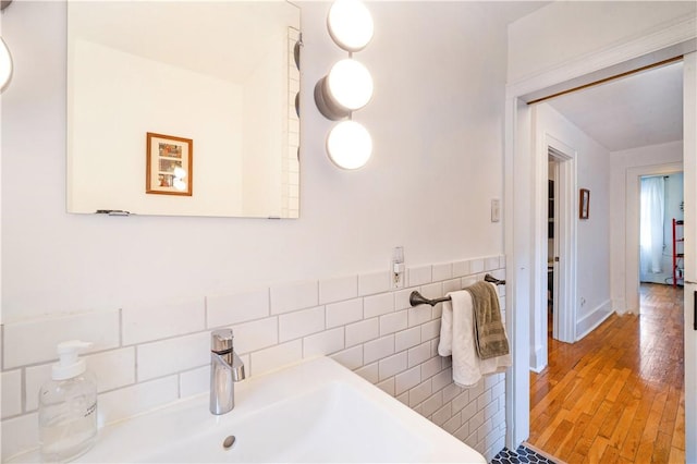 bathroom with tile walls, wood finished floors, and a sink
