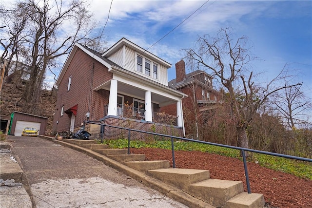 view of front of home with covered porch, a garage, an outdoor structure, and brick siding