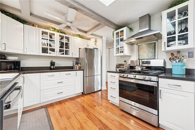 kitchen featuring wall chimney range hood, glass insert cabinets, light wood-style floors, and stainless steel appliances