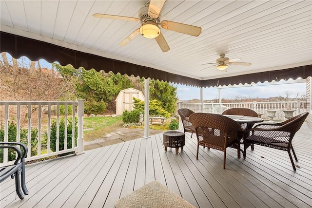 wooden deck featuring fence, a storage shed, outdoor dining space, a fire pit, and an outdoor structure