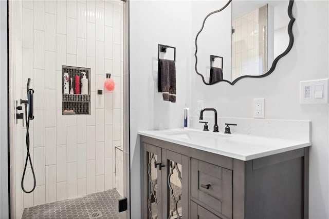 full bathroom with a tile shower and vanity