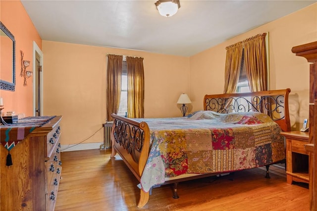 bedroom with radiator heating unit and wood finished floors