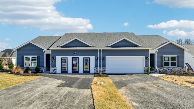 view of front of house featuring stone siding, driveway, a garage, and a shingled roof