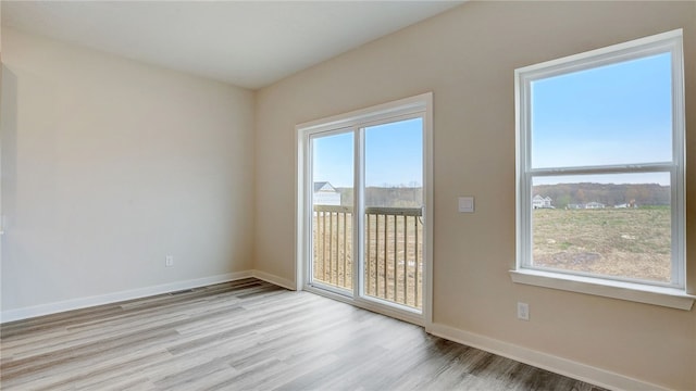 spare room with baseboards and wood finished floors