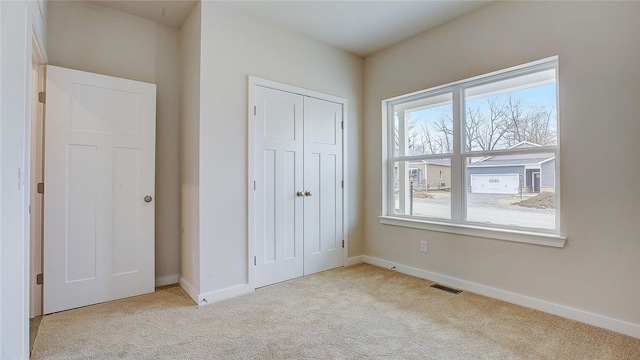 unfurnished bedroom featuring carpet flooring, a closet, baseboards, and visible vents