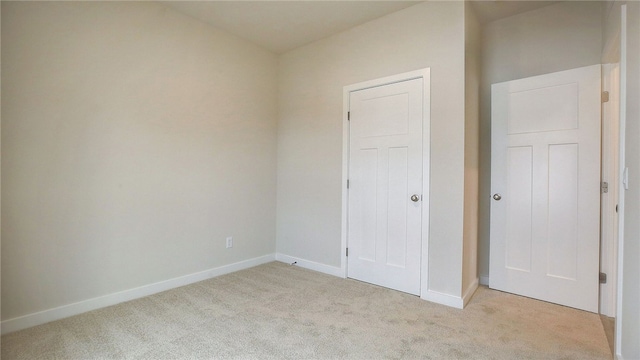 unfurnished bedroom featuring light carpet and baseboards