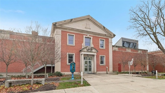 neoclassical home featuring driveway and brick siding
