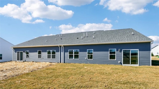 back of property with roof with shingles and a yard