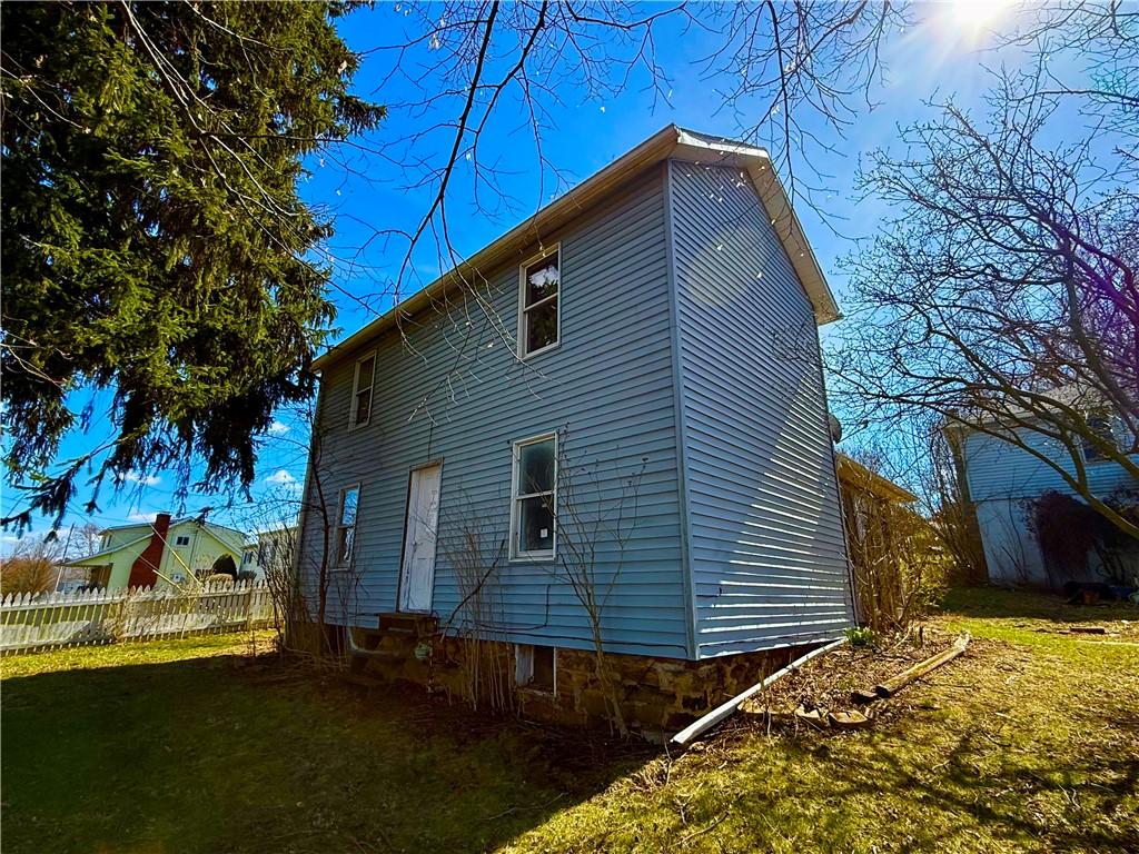 back of property featuring entry steps, fence, and a yard