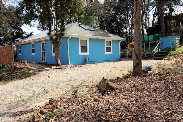 exterior space featuring concrete block siding, fence, and dirt driveway